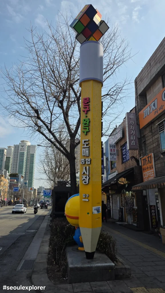 Landmark yellow pencil-shaped pillar sign at Dongdaemun Toy Market entrance